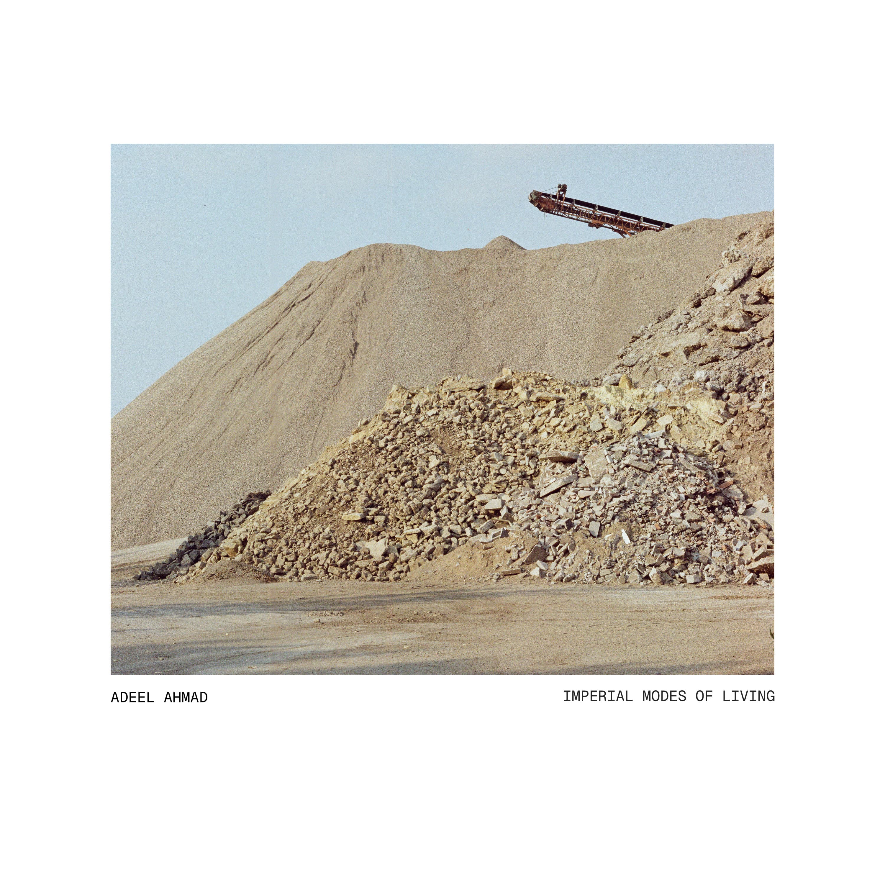 Imperial Modes of Living by Adeel Ahmad: quarry rubble and a conveyor beneath a pale blue sky, framed in white with the artist and album title below.